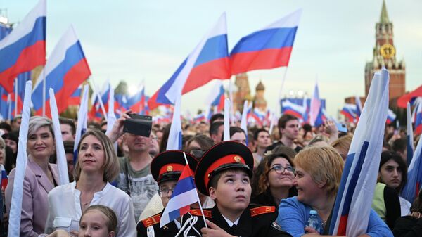 Люди с флагами РФ на праздничном концерте на Красной площади в Москве. Архивное фото - Sputnik Кыргызстан