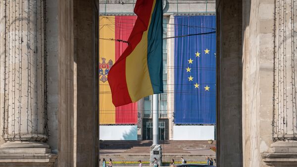 Люди проходят мимо здания правительства, украшенного флагами Европейского Союза и Молдовы в Кишиневе. Архивное фото - Sputnik Кыргызстан