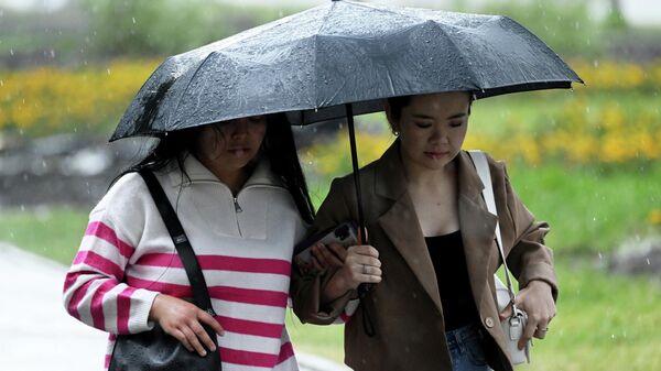 Девушки идут под зонтом во время дождя. Архивное фото  - Sputnik Кыргызстан