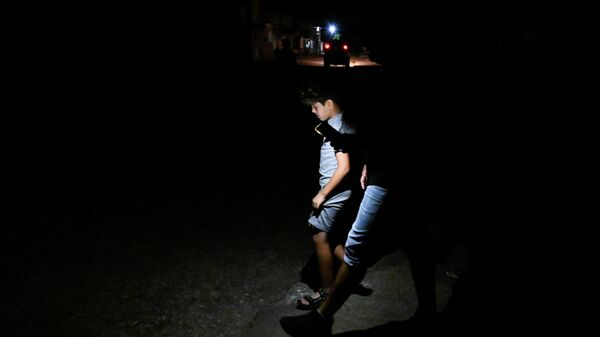 Мальчики идут по улице, используя свет мобильного телефона во время отключения электроэнергии. Архивное фото - Sputnik Кыргызстан