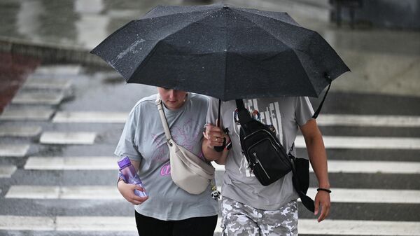 Семейная пара идут по улице с зонтом во время дождя. Архивное фото  - Sputnik Кыргызстан