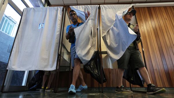 Избиратели выходят из кабин после пометки в своих бюллетенях для голосования в первом туре парламентских выборов на избирательном участке в Ла-Поссесьон на французском острове Реюньон в Индийском океане - Sputnik Кыргызстан