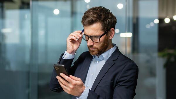 Мужчина со смартфоном в офисе. Иллюстративное фото - Sputnik Кыргызстан