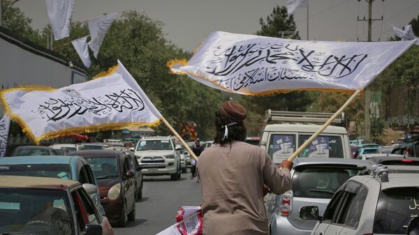 Мужчина размахивает флагами Талибана в Кабуле. Архивное фото - Sputnik Кыргызстан