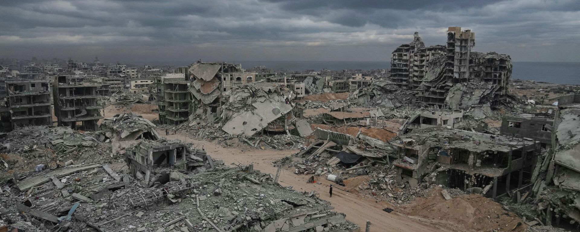 Перемещенные палестинцы идут среди разрушенных зданий в лагере беженцев Шати в городе Газа - Sputnik Кыргызстан, 1920, 13.10.2025