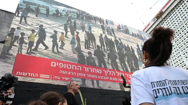 Люди смотрят прямую трансляцию освобождения заложников из сектора Газа в Тель-Авиве - Sputnik Кыргызстан