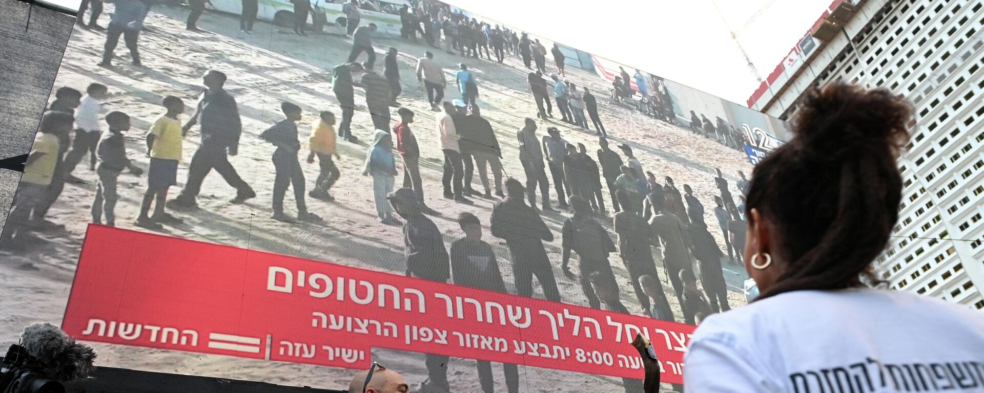 Люди смотрят прямую трансляцию освобождения заложников из сектора Газа в Тель-Авиве - Sputnik Кыргызстан, 1920, 13.10.2025