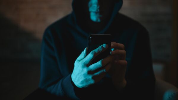 Мужчина в капюшоне со смартфоном в руках. Иллюстративное фото - Sputnik Кыргызстан