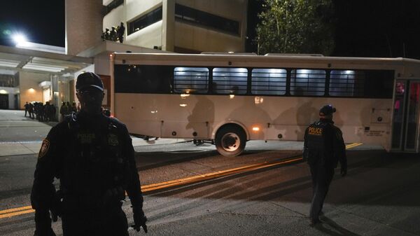 Портлендде АКШнын Иммиграция жана бажы кызматы (ICE) имаратынын сыртында турушкан укук коргоо органдарынын кызматкерлери автобустун жөнөшүн күтүп жаткан учурда - Sputnik Кыргызстан