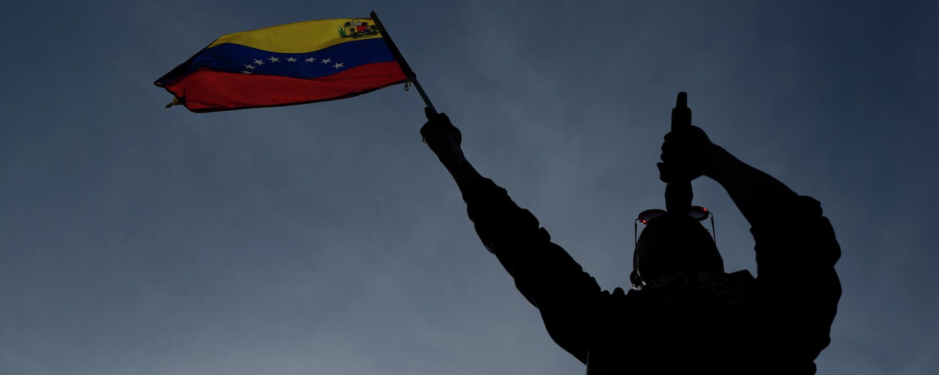 Мужчина с венесуэльским флагом говорит в микрофон в Каракасе. Архивное фото - Sputnik Кыргызстан, 1920, 18.12.2025