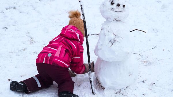 Снег. Девочка лепит снеговика - Sputnik Кыргызстан