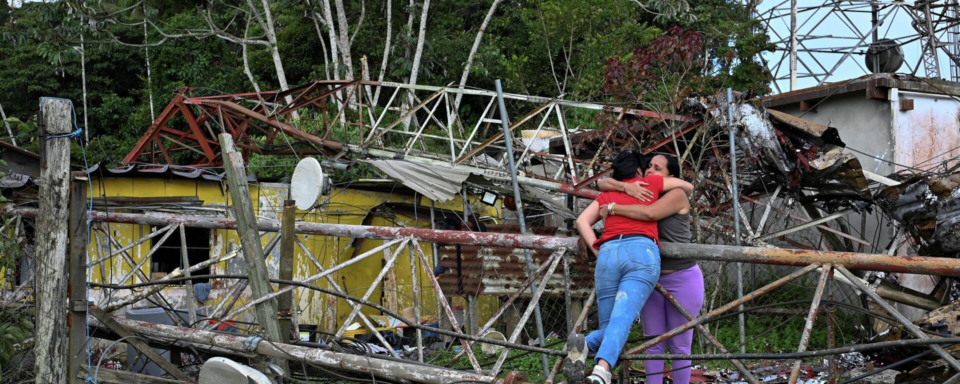 Электр линиясынын оператору Карлос Брачонун эжеси Эрика Утера АКШнын аба соккусунан телефон жана телевизор мунарасын талкалап, анын үйүнүн үстүнө кулап, кошунасын өлтүрүп, кызын жарадар кылган урандылардын жанында үй-бүлө мүчөсүн кучактап жатат. Каракастын чет жакаларында, Венесуэла. - Sputnik Кыргызстан, 1920, 07.01.2026