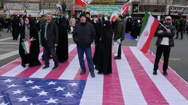 Иранцы стоят на баннере с изображением флага США - Sputnik Кыргызстан
