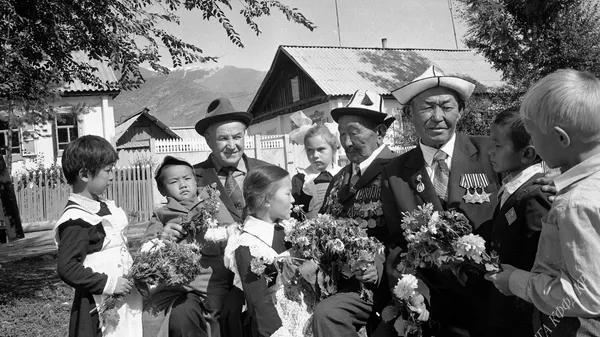 СССРдин “Даңк” ордени менен үч ирет сыйланган Дмитрий Темляков, Абдыкасым Карымшаков жана Осмон Чынтемиров окуучулар менен жолугуушуда. Күрмөнтү кыштагы, Түп району, 1984 - Sputnik Кыргызстан