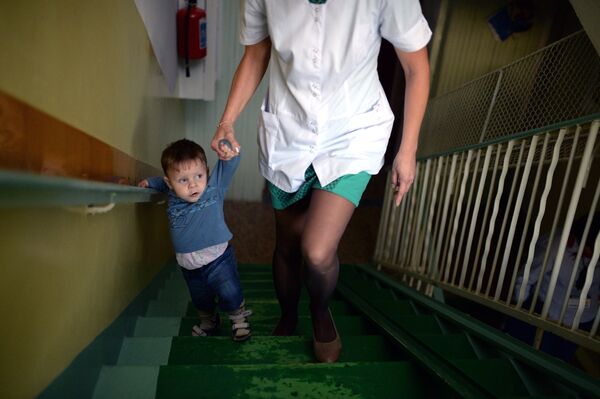 Архив: воспитанник одного из севастопольских домов ребенка поднимается по лестнице с воспитателем. - Sputnik Кыргызстан