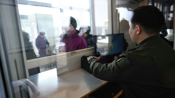 Сотрудник контрольно пропускного пункта кыргызско-казахской границы проверяет документы у граждан. Архивное фото - Sputnik Кыргызстан