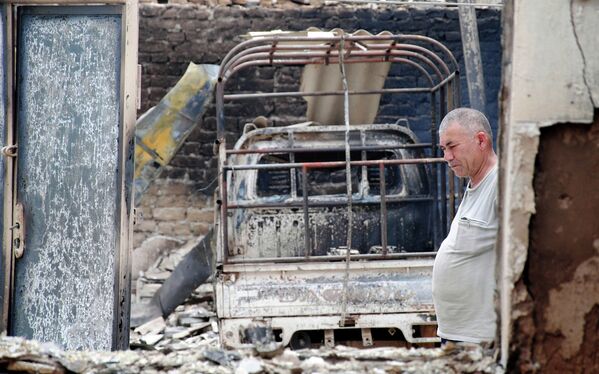 Мужчина стоит возле разрушенного гаража в деревне Шарк 16 июня 2010 года. - Sputnik Кыргызстан