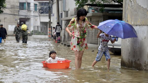 Женщина с детьми во время наводнения в Китае. Архивное фото - Sputnik Кыргызстан