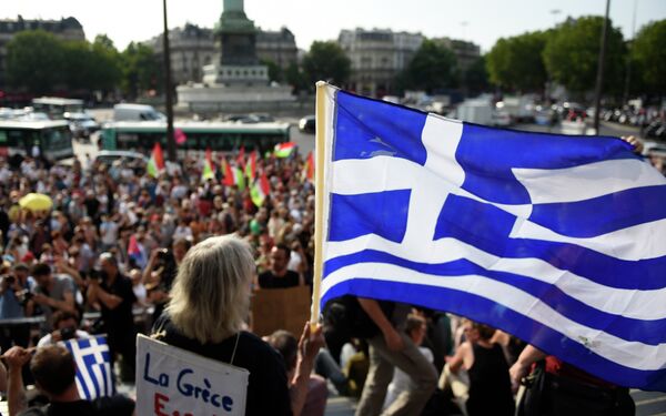 Протестующий держит греческий флаг, которая принимает участие в митинге в поддержку народа Греции на площади Бастилии в Париже. Архивное фото - Sputnik Кыргызстан