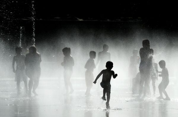 Аномальная жара установилась в пятницу в Испании — это уже вторая волна с конца прошлой недели, где в некоторых районах Испании уже отмечалось повышение температуры до 43-44 градусов.  Дети играют у фонтана на берегу реки Мансанарес в Мадриде - Sputnik Кыргызстан