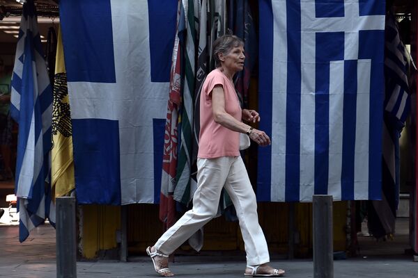 Женщина проходит мимо греческих флагов в центре Афины. Архивное фото - Sputnik Кыргызстан