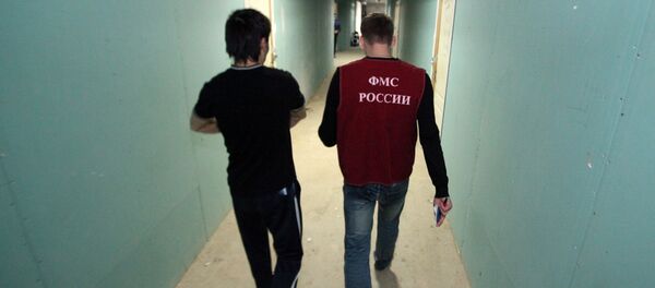 Иностранный рабочий идет по коридору общежития вместе с сотрудником отдела иммиграционного контроля Управления Федеральной Миграционной Службы (УФМС) России. Архивное фото - Sputnik Кыргызстан