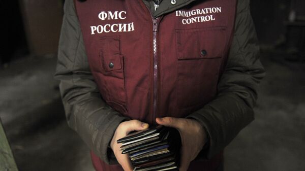 Сотрудник ФМС держит в руках паспорта задержанных во время рейда Федеральной миграционной службы. Архивное фото - Sputnik Кыргызстан