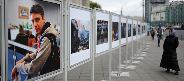 Жительница Москвы рассматривает работы погибшего на Украине фотокорреспондента Андрея Стенина у здания МИА Россия сегодня. Архивное фото - Sputnik Кыргызстан