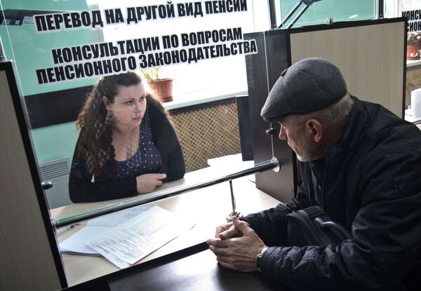 Сотрудница одного из отделений пенсионного фонда помогает мужчине заполнить документы. - Sputnik Кыргызстан