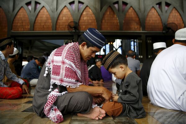 Отец с сыном сидят в мечети на утреннем праздничном намазе в Бангкоке (Таиланд) - Sputnik Кыргызстан