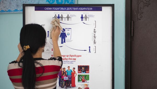 Девушка вытирает стенд с инструкцией пошаговых действий избирателя. - Sputnik Кыргызстан