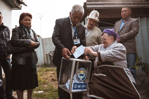 Жительница Бишкека бросает бюллетень в урну во время досрочного голосования - Sputnik Кыргызстан