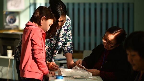 Женщина ищет себя в списке избирателей. Архивное фото - Sputnik Кыргызстан