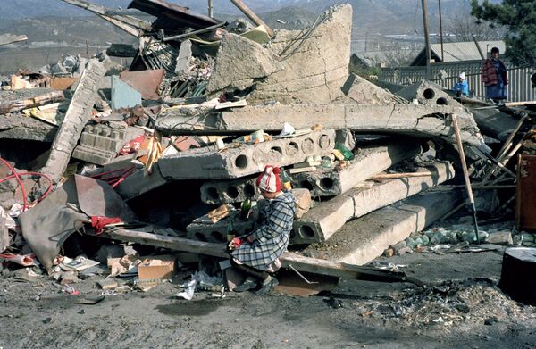 Ребенок сидит на развалинах родного дома, разрушенного в результате сильнейшего землетрясения в Армении. Архивное фото - Sputnik Кыргызстан