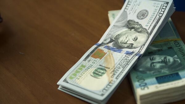 Пачка сто долларовых и пяти тысячи сомовых купюр на столе. Архивное фото - Sputnik Кыргызстан