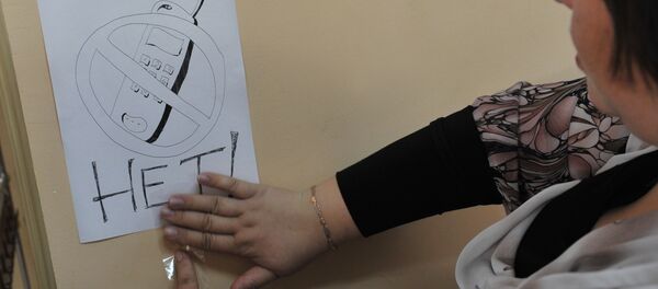 Учительница развешивает плакаты, напоминающие о запрете пользоваться мобильными телефонами при сдаче экзамена. Архивное фото - Sputnik Кыргызстан