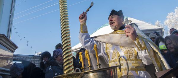 Священник обливает священной водой на церковном празднике крещения Христа. Архивное фото Священник обливает священной водой на церковном празднике крещения Христа. Архивное фото - Sputnik Кыргызстан