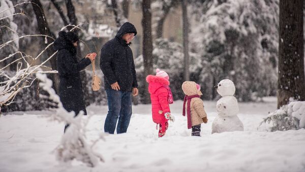 Семья возле снеговика во время снегопада. Архивное фото - Sputnik Кыргызстан