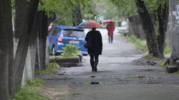 Женщина с зонтом идет по улице в Бишкеке. Архивное фото - Sputnik Кыргызстан