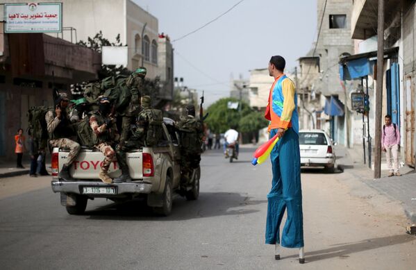 Палестиналык жаран Газа секторунун түндүк жагындагы көчөлөрдүн биринде кетип бара жаткан Хамас согушкерлерин карап турат. - Sputnik Кыргызстан