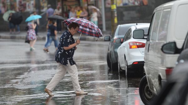 Женщина с зонтом переходит дорогу во время сильного дождя. Архивное фото  - Sputnik Кыргызстан