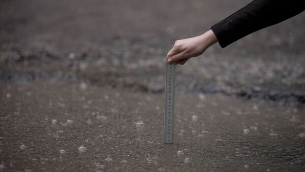 Девушка измеряет глубину лужи. Архивное фото - Sputnik Кыргызстан