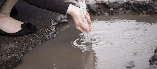 Девушка измеряет глубину ямы с лужей. Архивное фото - Sputnik Кыргызстан