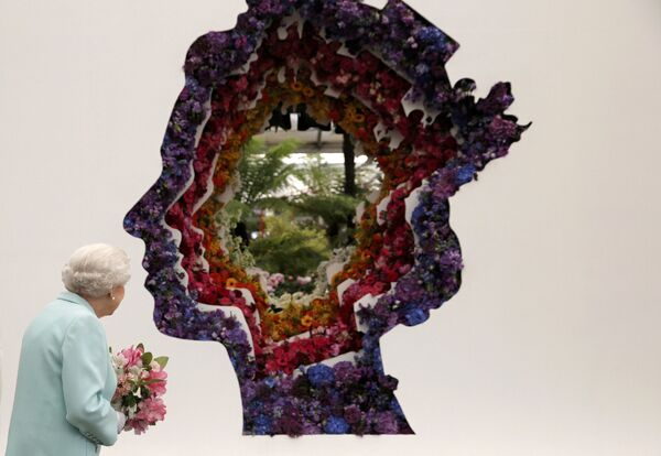 Улуу Британиянын королевасы Елизавета II гүлдөрдөн жасалган өзүнүн элесин Лондондогу  Chelsea Flower Show  көргөзмөсүндө карап жатат. - Sputnik Кыргызстан