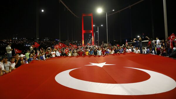 Проправительственные демонстранты держат гигантский турецкий флаг во время марша через Босфорский мост в Стамбуле, Турция. Архивное фото - Sputnik Кыргызстан