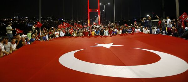 Проправительственные демонстранты держат гигантский турецкий флаг во время марша через Босфорский мост в Стамбуле, Турция. Архивное фото - Sputnik Кыргызстан