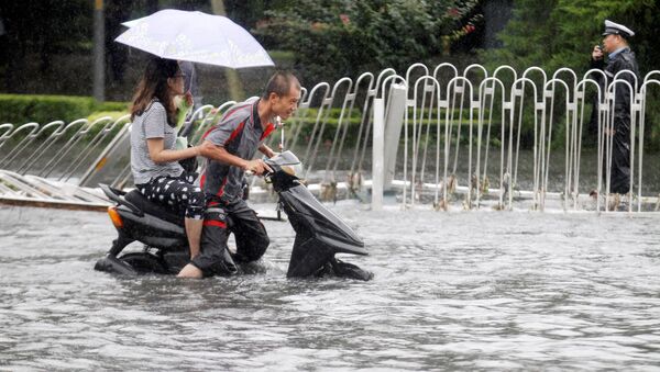 Мужчина и женщина едут на скутере во время наводнения в Пекине. Архивное фото - Sputnik Кыргызстан