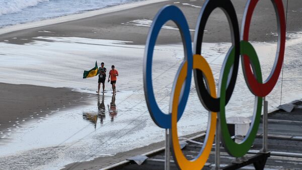 Болельщики идут по пляжу Копакабана рядом с ареной пляжного волейбола в Рио-де-Жанейро, где проходят соревнования XXXI летних Олимпийских игр. - Sputnik Кыргызстан