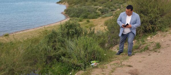 Полномочный представитель правительства в Иссык-Кульской области Асхад Акибаев снимает на телефон мусор на пляжах Тонского района - Sputnik Кыргызстан