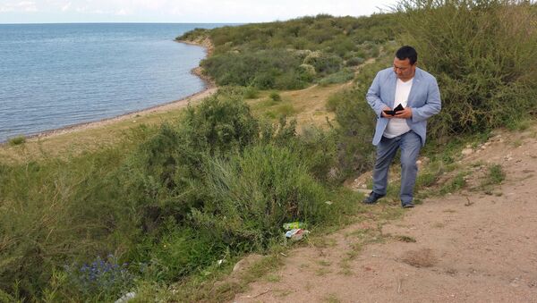 Полномочный представитель правительства в Иссык-Кульской области Асхад Акибаев снимает на телефон мусор на пляжах Тонского района - Sputnik Кыргызстан